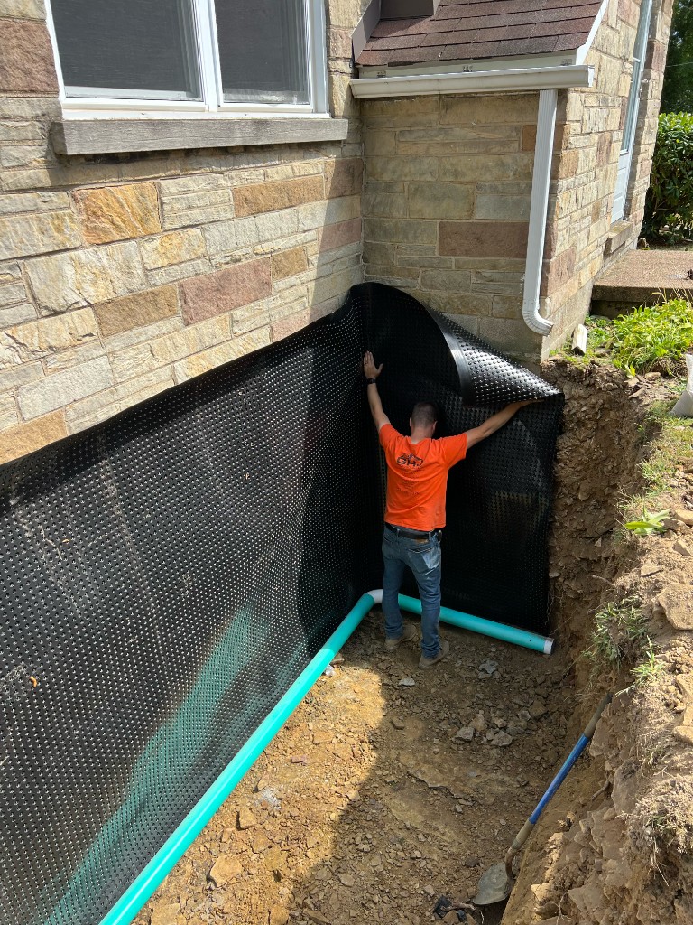 GHJ Excavation crew installing dimple board and drainage pipe for a French drain system